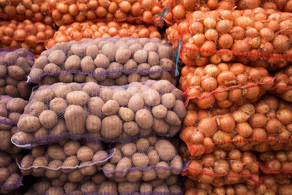 bags of onions and potatoes next to each other.