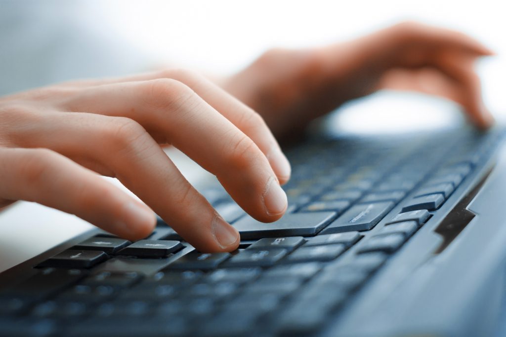 Close-up of hands typing on keyboard